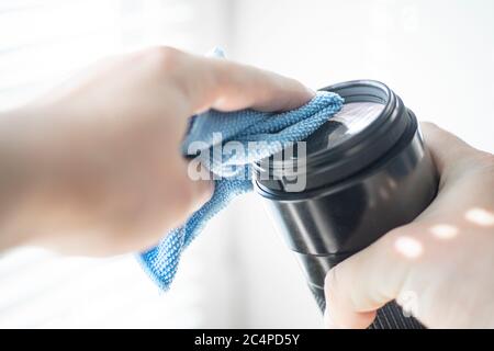 la mano tiene un panno in microfibra per pulire l'obiettivo della fotocamera dslr rimuove la polvere dal vetro dell'obiettivo Foto Stock