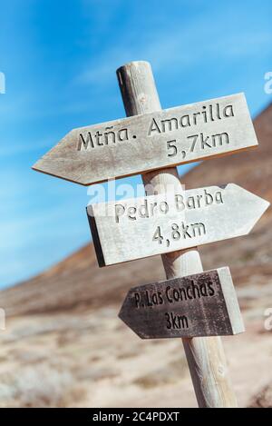 Un cartello in legno nel mezzo di la Graciosa, ad un incrocio di piste polverose, che punta a varie località, l'isola di Graciosa, Isole Canarie, Spagna Foto Stock