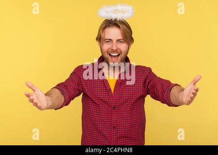 Vieni tra le mie braccia! Divertente ragazzo bearded amabile con saint nimbus sopra la testa che tende le mani alla macchina fotografica e sorridente amichevole, andando abbracciare, condividere l'amore Foto Stock