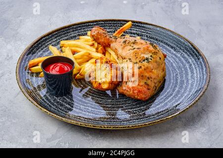 Coscia di pollo al forno con patatine fritte, mais alla griglia e ketchup sul tavolo Foto Stock