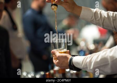 Il barman versa l'alcool in un bicchiere. Primo piano. Foto Stock