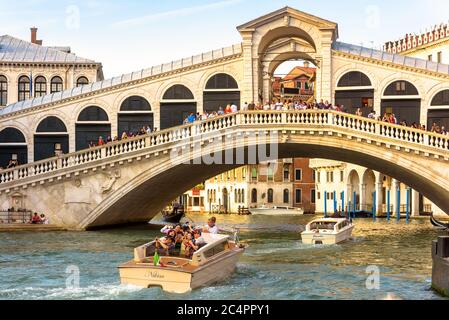 Venezia - 18 maggio 2017: Taxi acqueo con turisti naviga sul Canal Grande sotto il Ponte di Rialto a Venezia. Il Ponte di Rialto è un famoso punto di riferimento Foto Stock