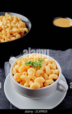 Mac e formaggio con salsa di formaggio vegano su fondo nero. Angolo alto Foto Stock