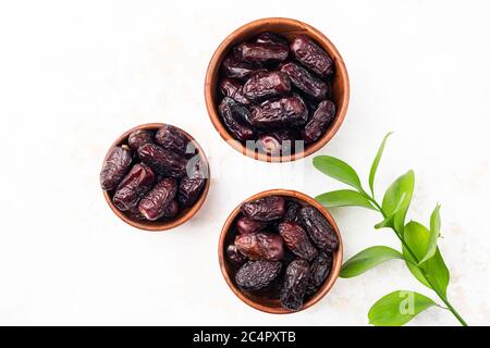 Datteri essiccati in ciotola di legno isolata su sfondo bianco. Date Medjool Foto Stock