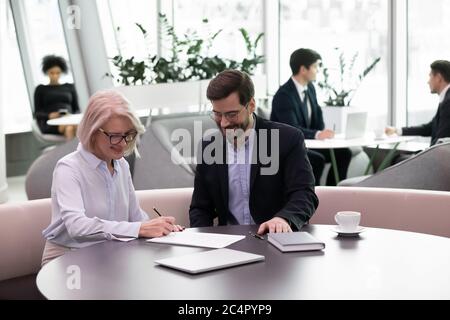 Donna di affari felice anziana firmano il contratto che fa l'affare con il socio Foto Stock