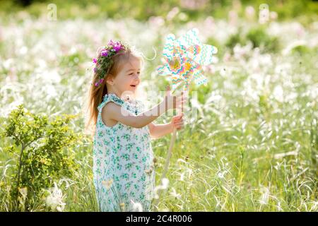 Carina bambina sorridente estate nel campo tenendo un mulino a vento Foto Stock