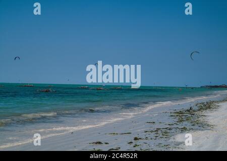 Una folla di kite surfisti in acqua al largo della costa di Jambiani a Zanzibar, Tanzania Foto Stock