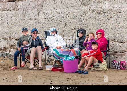 Garretstown, Cork, Irlanda. 28 Giugno 2020. Le famiglie Coveney e Marron si sono tutte avvolte e riparate in una fresca giornata estiva sulla spiaggia di Garrettstown, Co. Cork, Irlanda. I Coveney avrebbero dovuto volare in Portogallo per le loro vacanze in famiglia oggi, ma il viaggio è stato annullato a causa della crisi del Covid-19. LtoR; Seán e Pat Coveney, Mary e Rory Marron, Niamh, Caitriona e Padraig Coveney si sono avvolti in una fresca giornata estiva sulla spiaggia di Garrettstown, Co. Cork, Irlanda. - Credit David Creedon / Alamy Live News Foto Stock