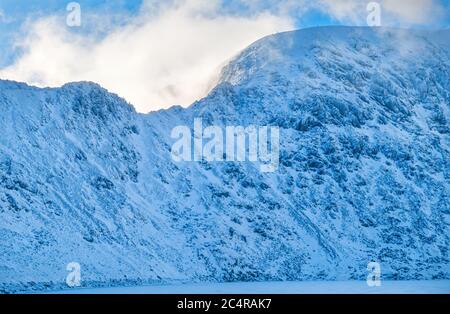 Striding Edge e Helvellyn nella neve invernale sopra il Tarn rosso congelato, Distretto dei Laghi inglesi, Cumbria, Inghilterra, Regno Unito Foto Stock