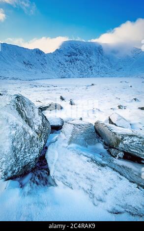 Striding Edge e Helvellyn nella neve invernale sopra il Tarn rosso congelato, Distretto dei Laghi inglesi, Cumbria, Inghilterra, Regno Unito Foto Stock