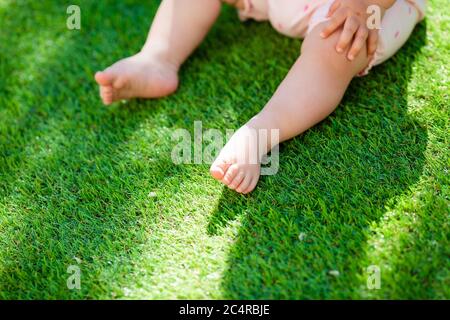 i piedi del bambino in estate sul prato verde, primo piano, spazio per il testo Foto Stock