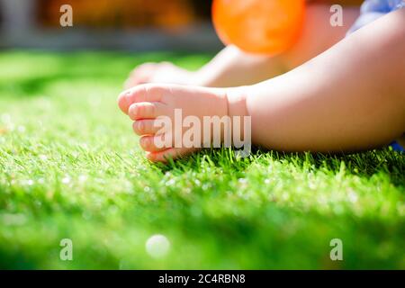 i piedi del bambino in estate sul prato verde, primo piano, spazio per il testo Foto Stock