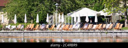 Sedie a sdraio e ombrelloni sono allineati al ristorante sul lungolago del lago Starnberg. È il momento di rilassarsi e rilassarsi! Foto Stock