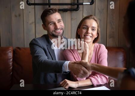 I coniugi si incontrano in un bar con un agente di viaggio accettano l'offerta turistica Foto Stock