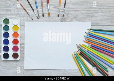 Strumenti per il disegno, la cancelleria, il luogo di lavoro dell'artista. Pittura e matite e carta trasparente su tavolo di legno, vista dall'alto, posa piatta, spazio di copia. Disegno scolastico Foto Stock