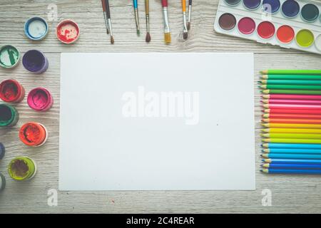 Strumenti per il disegno, la cancelleria, il luogo di lavoro dell'artista. Pittura e matite e carta trasparente su tavolo di legno, vista dall'alto, posa piatta, spazio di copia. Disegno scolastico Foto Stock