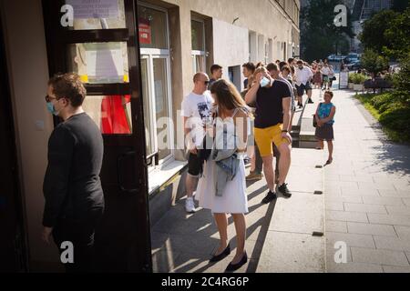 Varsavia, Polonia. 28 Giugno 2020. La gente attende in fila ad un seggio a Varsavia, Polonia, il 28 giugno 2020. Domenica mattina si sono aperte le seggi elettorali per il primo turno delle elezioni presidenziali polacche, che si prevedevano si svolgeranno il 10 maggio ma sono state ritardate dalla pandemia della COVID-19. Il nuovo capo di stato polacco sarà eletto in un periodo di fuga, i sondaggi di uscita del primo turno delle elezioni presidenziali hanno mostrato Domenica sera, ha riferito l'Agenzia Stampa polacca. Credit: Jap Arriens/Xinhua/Alamy Live News Foto Stock