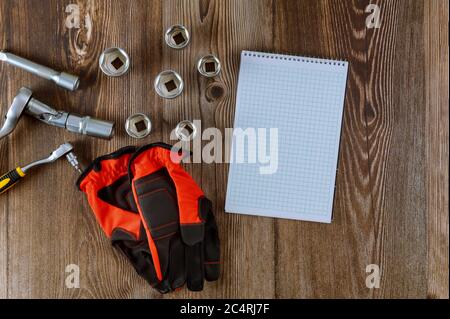 Regolazione del blocco note a spirale degli attrezzi per il meccanico automatico, guanti da lavoro in chiave per l'automobile su fondo di legno Foto Stock