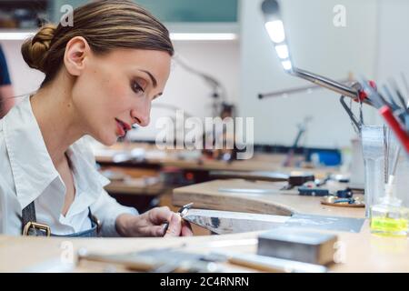 Gioielliere che lavora con gli attrezzi su un pezzo di gioielleria Foto Stock