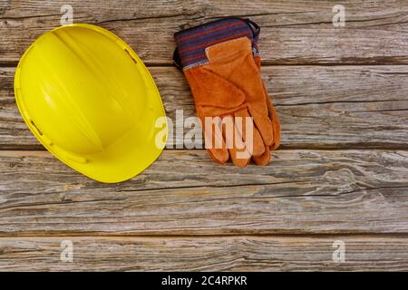 Standard di sicurezza dell'attrezzatura per cantieri, guanti di sicurezza gialli protettivi per elmetti su sfondo di legno Foto Stock