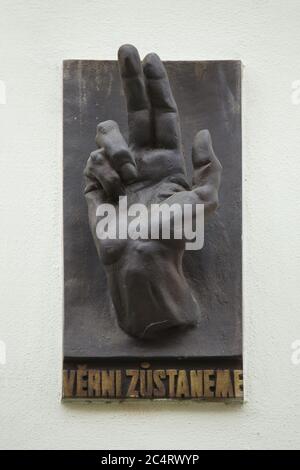 Lapide commemorativa dedicata ai caduti durante l'insurreazione di Praga nel maggio 1945, posta sul muro di una casa a Na Švihance Street nel quartiere Vinohrady di Praga, Repubblica Ceca. L'iconica mano benedetta con l'iscrizione ceca "Věrni zůstaneme" (noi rimarriamo fedeli) è stata progettata dallo scultore ceco modernista Karel Pokorný (1945). Foto Stock