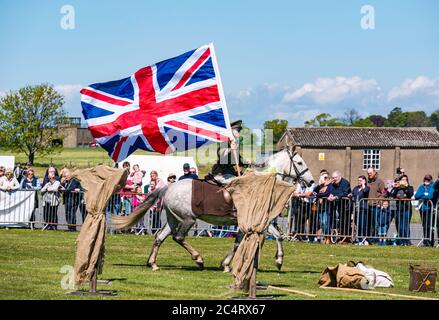 Les Amis D'Onno squadra di stunt equestre con soldato a cavallo che porta grande bandiera Union Jack, evento bellico, East Fortune, East Lothian, Scozia Foto Stock