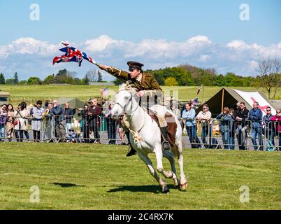 Team di stunt equestri Les Amis D'Onno con soldato che si carica a cavallo con Union Jack durante l'evento bellico, East Fortune, East Lothian, Scozia, Regno Unito Foto Stock