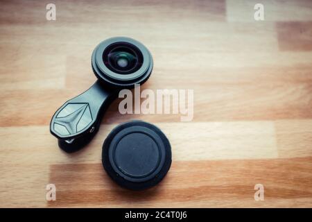 Obiettivo della fotocamera per telefoni cellulari posto sulla superficie di legno Foto Stock