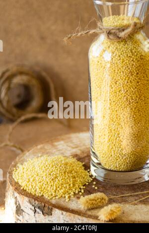 Miglio in un vaso di vetro su un supporto di legno, dopo è un orecchio di grano Foto Stock