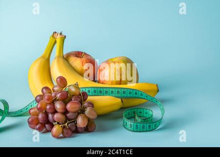 Frutta matura e nastro di misurazione su sfondo blu. Il concetto di dieta e di alimentazione adeguata. Posiziona per il testo. Foto Stock