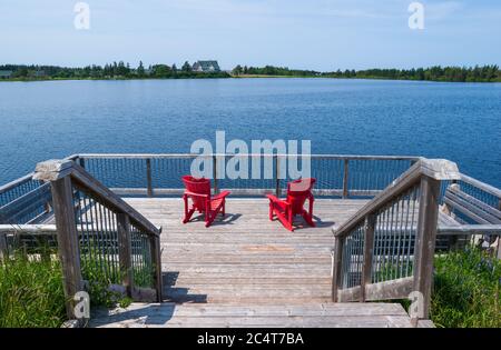 Due sedie rosse su una piattaforma di osservazione che si affaccia sul lago Dalvay e il Dalvay-by-the-Sea Hotel. Prince Edward Island National Park, Canada. Foto Stock