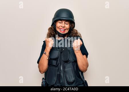 Media età bella donna soldato indossare uniforme bullettproof e casco di sicurezza festeggiando sorpreso e stupito per il successo con le braccia sollevate e e. Foto Stock