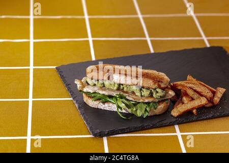 Primo piano di un gustoso sandwich vicino alle patatine fritte una piastra di pietra nera Foto Stock