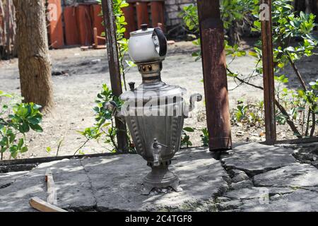 Una teiera su un samovar in un cortile estivo si erge su pietre grigie Foto Stock