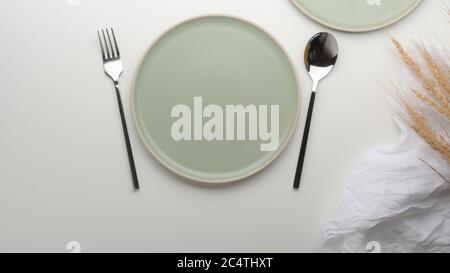 Vista dall'alto di piatti in ceramica turchese, argenteria, tovagliolo e grano dorato decorati sul tavolo da pranzo Foto Stock