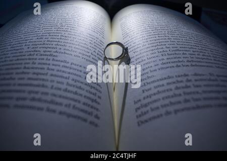 Un anello di nozze nel mezzo del libro che getta un'ombra a forma di cuore sulle pagine Foto Stock