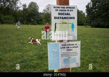 Segni che affrontano le preoccupazioni su animali domestici che trasportano COVID-19 & che ricordano la gente di distanza sociale sono visti in un parco del cane a Linn occidentale, Ore., il 6/27/2020. Foto Stock