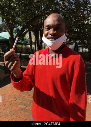 Johannesburg, Sudafrica. 27 Giugno 2020. Pocha Ngulube mostra la sigaretta, che ha acquistato per 5 Rand (26 centesimi) - invece di 3 Rand (16 centesimi) come prima - ancora relativamente poco costoso sul mercato nero. In considerazione dei livelli di reddito e del forte aumento dei prezzi, le sigarette vengono di solito vendute singolarmente. Nella lotta contro il coronavirus, il governo sudafricano ha imposto alla fine di marzo uno dei più rigidi malfeuda del mondo, che include anche un divieto del tabacco. (A dpa-Korr 'il tabacco da stronzo nel Capo: Il Sudafrica mette i suoi fumatori al ritiro') credito: Ralf Krüger/dpa/Alamy Live News Foto Stock