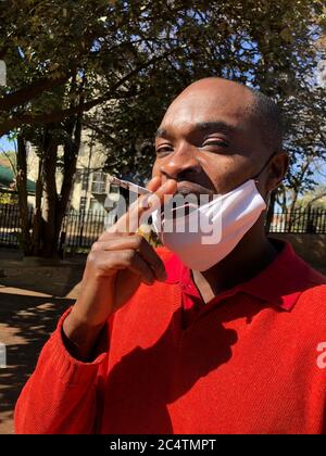 Johannesburg, Sudafrica. 27 Giugno 2020. Pocha Ngulube gode della sigaretta, che ha acquistato per 5 Rand (26 centesimi) - invece di 3 Rand (16 centesimi) - relativamente poco costoso sul mercato nero. In considerazione dei livelli di reddito e del forte aumento dei prezzi, le sigarette vengono di solito vendute singolarmente. Nella lotta contro il coronavirus, il governo sudafricano ha imposto alla fine di marzo uno dei più rigidi malfeuda del mondo, che include anche un divieto del tabacco. Credit: Ralf Krüger/dpa/Alamy Live News Foto Stock