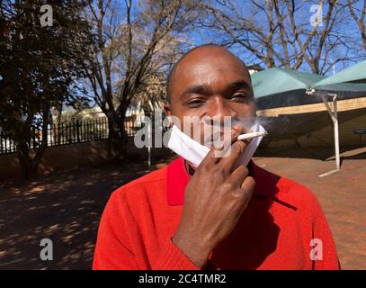Johannesburg, Sudafrica. 27 Giugno 2020. Pocha Ngulube gode della sigaretta, che ha acquistato per 5 Rand (26 centesimi) - invece di 3 Rand (16 centesimi) - relativamente poco costoso sul mercato nero. In considerazione dei livelli di reddito e del forte aumento dei prezzi, le sigarette vengono di solito vendute singolarmente. Nella lotta contro il coronavirus, il governo sudafricano ha imposto alla fine di marzo uno dei più rigidi malfeuda del mondo, che include anche un divieto del tabacco. (A dpa-Korr 'il tabacco da stronzo nel Capo: Il Sudafrica mette i suoi fumatori al ritiro') credito: Ralf Krüger/dpa/Alamy Live News Foto Stock