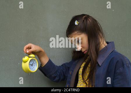 Primo piano di una giovane donna caucasica preoccupata che guarda una sveglia Foto Stock