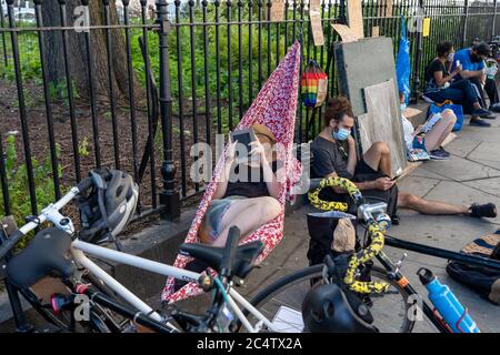 New York, Stati Uniti. 24 Giugno 2020. I manifestanti si trovano in un parco fuori dal municipio durante la dimostrazione.come il movimento Occupy Wall Street che ha assunto il controllo del Parco Zuccotti per mesi, il gruppo sta ora realizzando stazioni di cibo, mediche e di informazione per assistere i manifestanti che vogliono rimanere. Tra le altre richieste, gli attivisti cercano il definanziamento del dipartimento di polizia. Credit: SOPA Images Limited/Alamy Live News Foto Stock