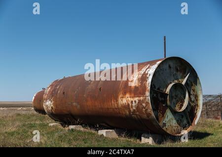 Un vecchio barile arrugginito abbandonato si trova all'aperto sull'erba. Foto Stock