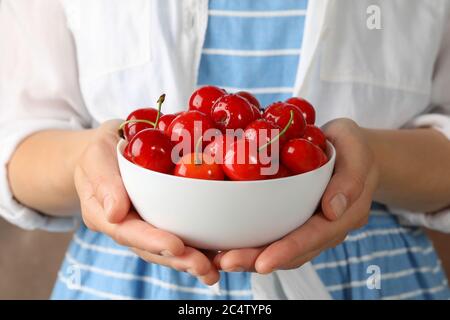 Donna tiene il recipiente con ciliegia rossa fresca, primo piano Foto Stock