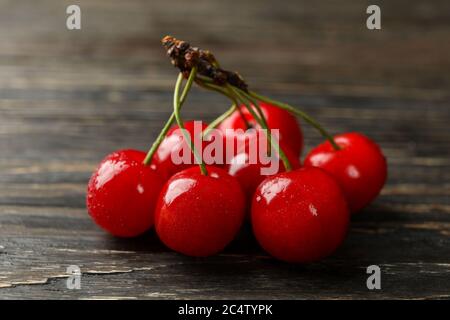 Ciliegio rosso fresco su sfondo di legno, primo piano Foto Stock