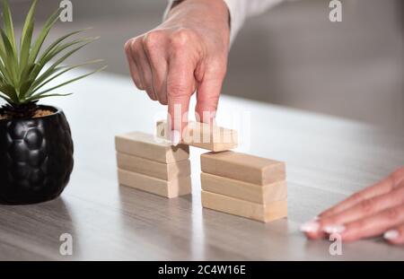 Mano femmina costruzione di un ponte con blocchi di legno; concetto di associazione Foto Stock