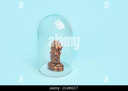 Concetto di isolamento o quarantena a Singapore. Rimani a casa. Idea pandemica con il simbolo della testa leone di Singapore e gli occhiali e spazio copia su sfondo blu pastello. Simbolo della testa leone di Singapore Foto Stock