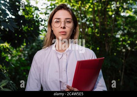 Giovane ingegnere agricolo che lavora in serra. Giovane scienziata femminile che guarda la macchina fotografica Foto Stock