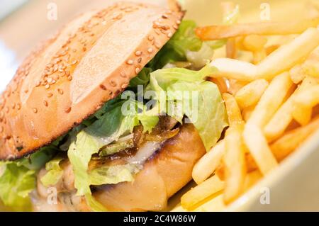 Fuoco selettivo di un sandwich di prosciutto con patatine fritte in una piastra gialla Foto Stock