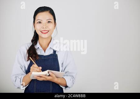 Portrtait di sorridere giovane cameriera scrivere ordine del cliente Foto Stock
